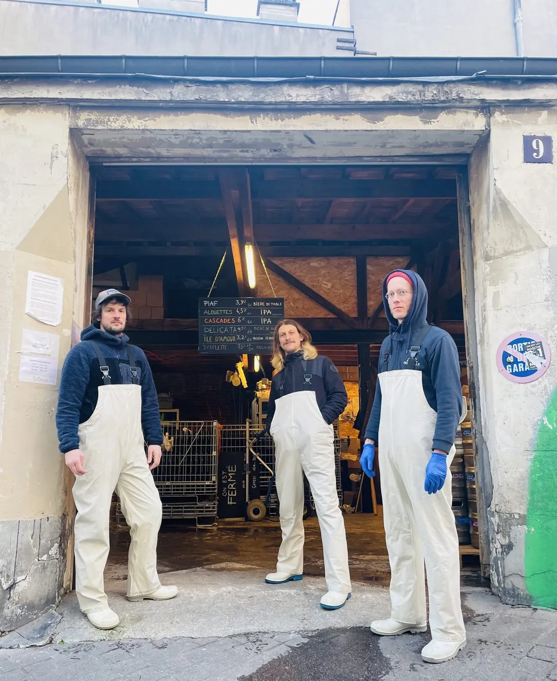 Les trois brasseurs en salopettes blanches devant la porte de garage du 9 rue Jean-Baptiste Dumay